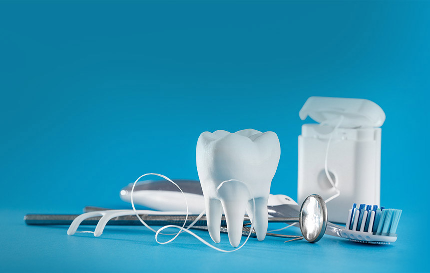 Toothbrush, floss, and large tooth on a blue background