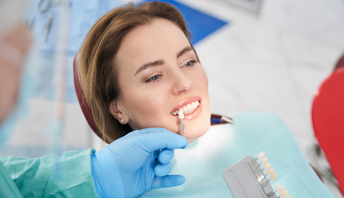 Dentist comparing color of implants to a female patient's teeth